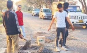 सड़क पर गड्ढे भरते बहजोई के युवक ।